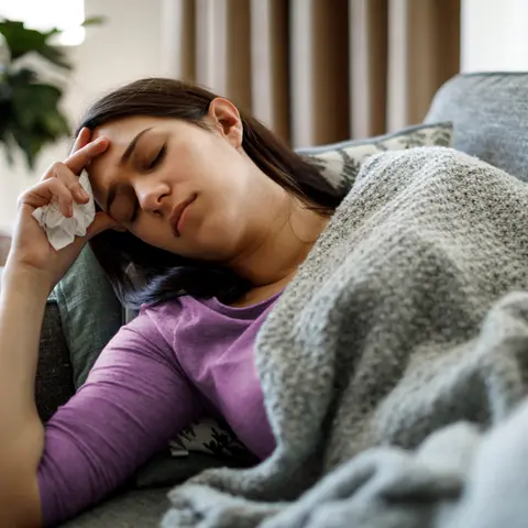Junge Frau liegt mit einer Erkältung auf dem Sofa