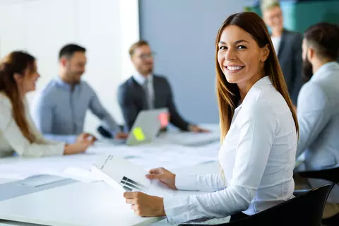 Junge Frau im Sitzungszimmer schaut in die Kamera und lacht - Jobs bei Schwabe Pharma